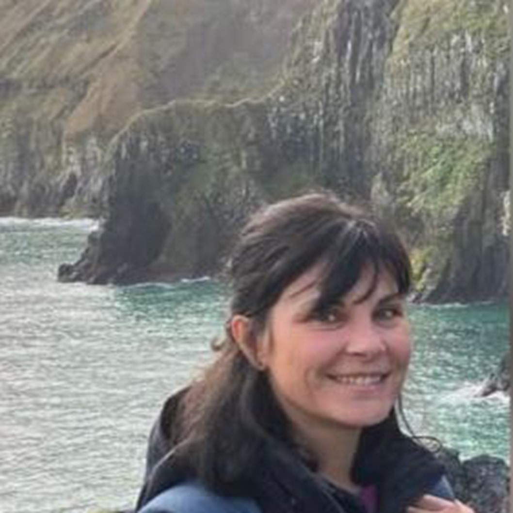 Professor Margherita Pieraccini, Professor of Law at the University of Bristol, standing outside with coastal bays and cliffs in the background.